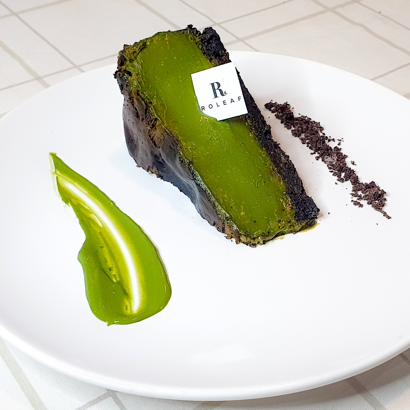 Roleaf burnt matcha oreo cheesecake on plate with logo tag